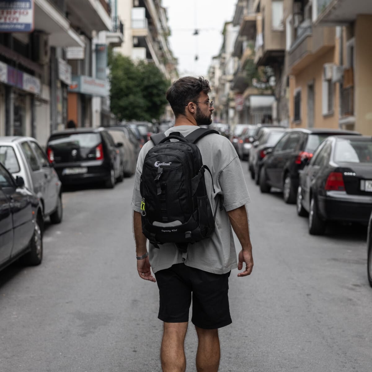 Σακίδιο πλάτης μαύρο με άνδρα να το φοράει και να περπατάει στην πόλη .