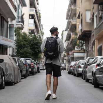Σακίδιο πλάτης μαύρο με άνδρα να το φοράει και να περπατάει στην πόλη .