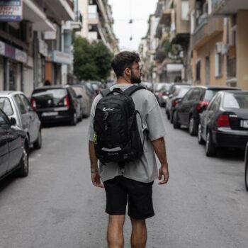 Σακίδιο πλάτης μαύρο με άνδρα να το φοράει και να περπατάει στην πόλη .