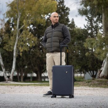 Βαλίτσα μεσαία σκληρή σε σκούρο μπλε χρώμα με άνθρωπο να την κρατάει