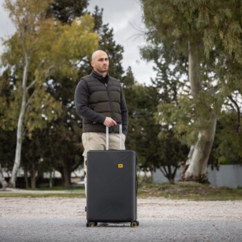 Βαλίτσα μεγάλη σκληρή σε μαύρο χρώμα με άνθρωπο να την κρατάει